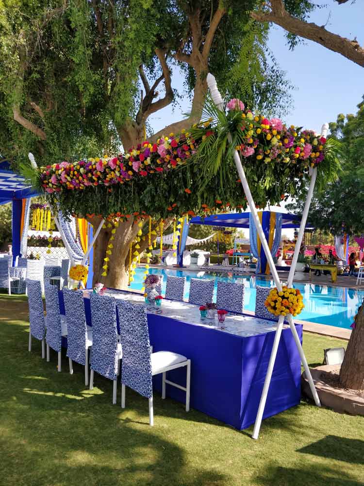 A table set outdoors with flowers hung above it A table set outdoors with flowers hung above it