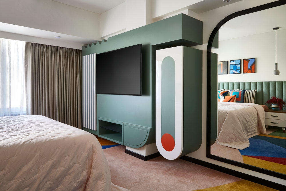 A room with a green headboard and green TV unit