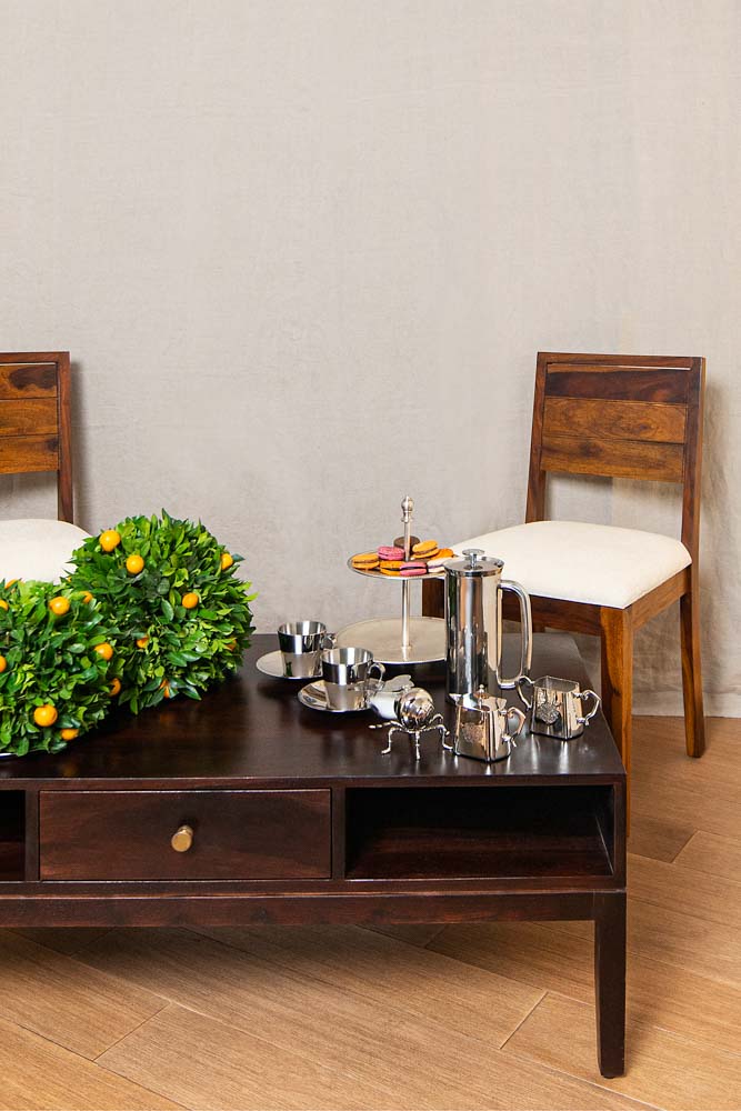 A centre table with some stainless steel utensils on it and a couple of chairs behind it