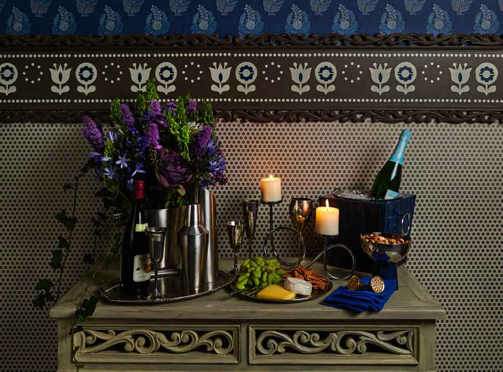 A table with a bar set up placed on top of it with some cheese, grapes etc
