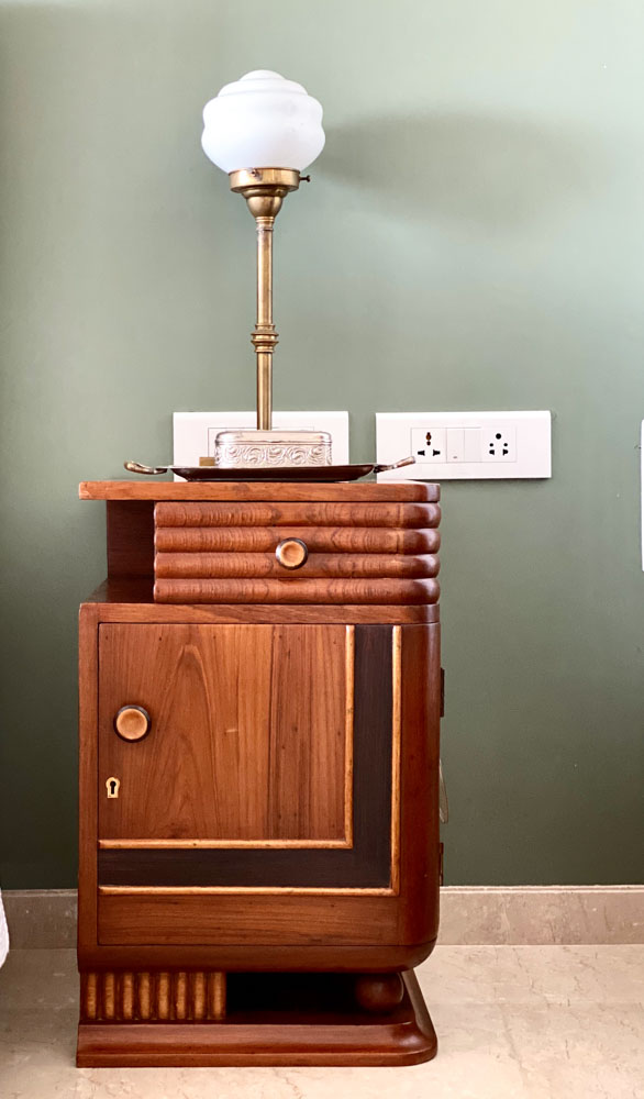 A wooden side-table in front of a green wall
