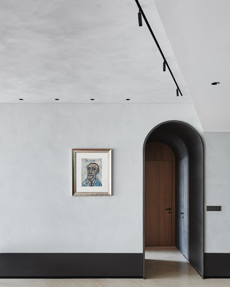 A grey wall with a painting and black skirting