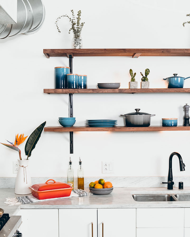 a clean kitchen counter with crockery and a flower vase