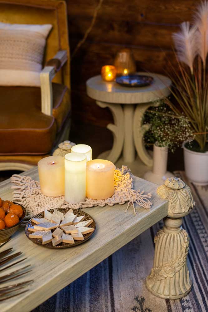 A corner of a coffee table with candles and sweets on it