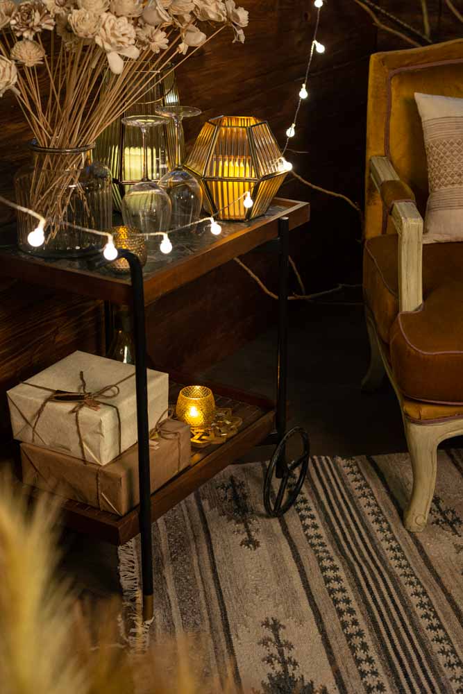 A two tier trolley with candles and glass flower vases on it