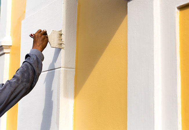 Man Painting wall with brush on a building - Asian Paints