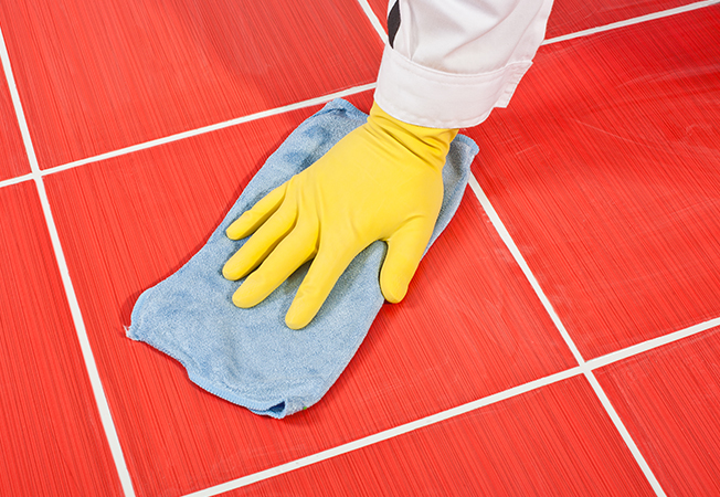 Worker cleaning tiles with yellow gloves and blue towel - Asian Paints