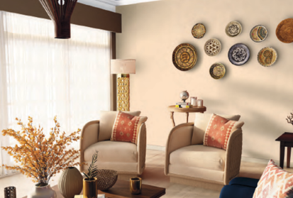A cozy living room with Tinge Of shade walls and white curtains, an armchair, a table with decor pieces and a flower vase