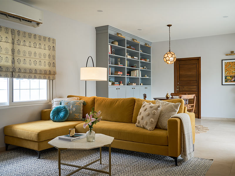 Comfortable yellow sofa & library for the family to unwind in after a long day - Beautiful Homes