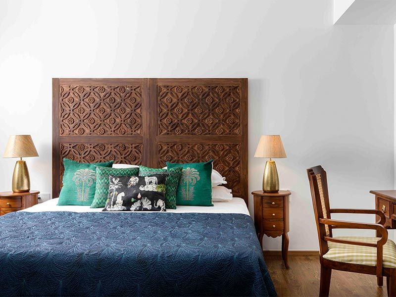 Bed in guest room with hand carved wooden headboard - Beautiful Homes
