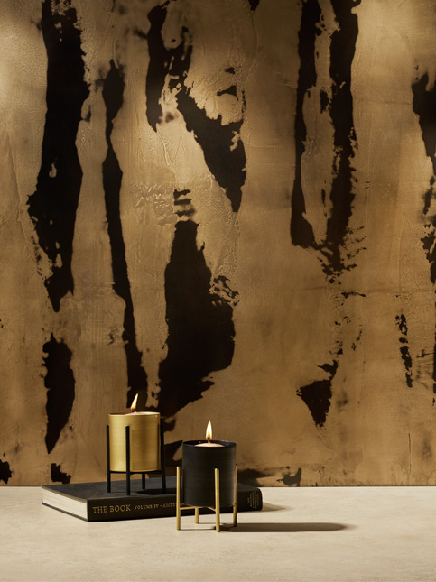 Two lit candles on books against a textured wall - Beautiful Homes