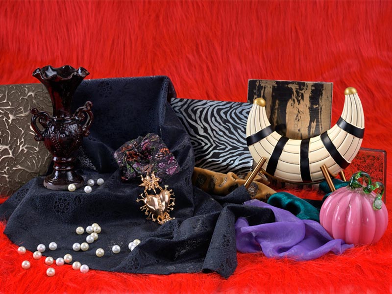 A collection of decorative items including a vase, pearls, and textiles on a vibrant red background – Beautiful Homes
