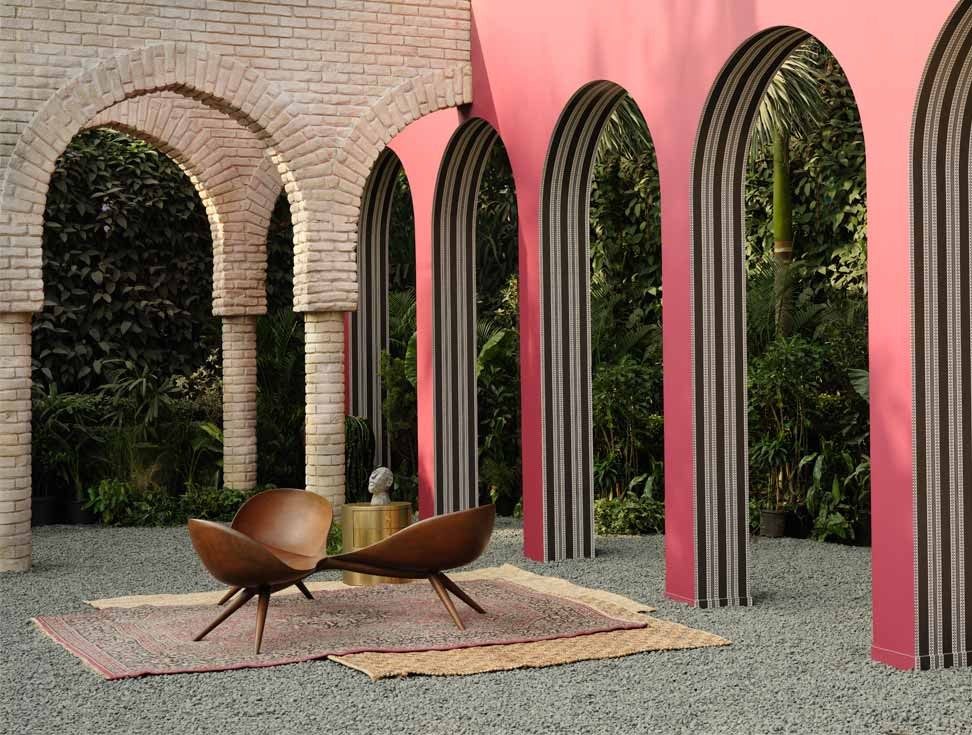 Stylish outdoor space with pink arched walls, brick archways, and wooden lounge chairs – Beautiful Homes