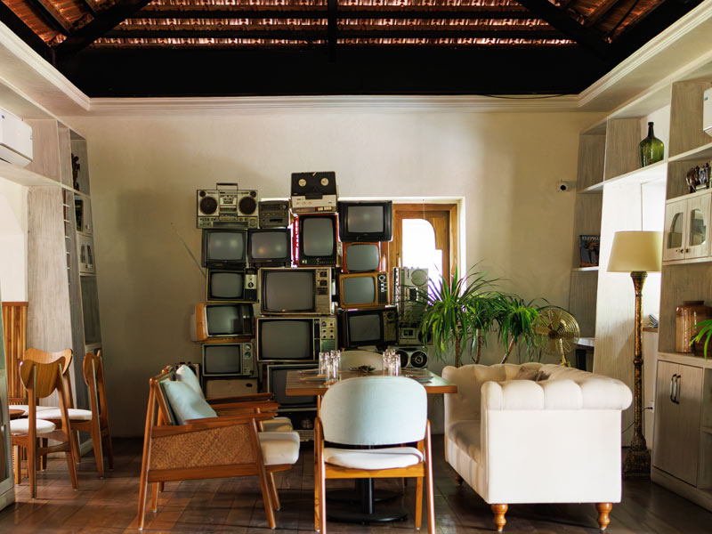 A modern rustic lounge with wooden interiors, pastel seating, and a vintage TV wall centerpiece - Beautiful Homes