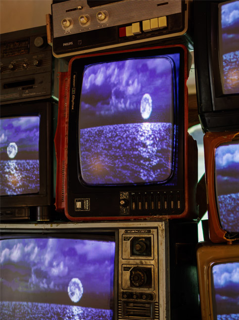 Wall of vintage TVs displaying a moonlit ocean in blue hues – Beautiful Homes