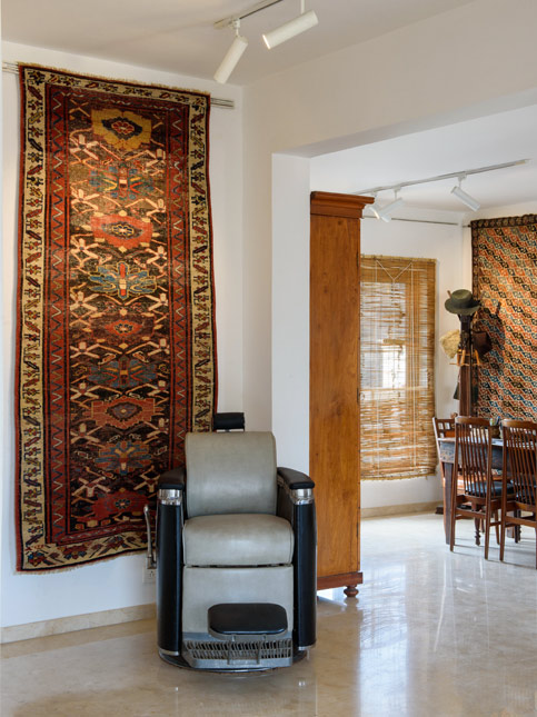 A barber chair sits beneath a patterned rug in a warmly lit room adorned with traditional textiles and wooden furniture - Beautiful Homes