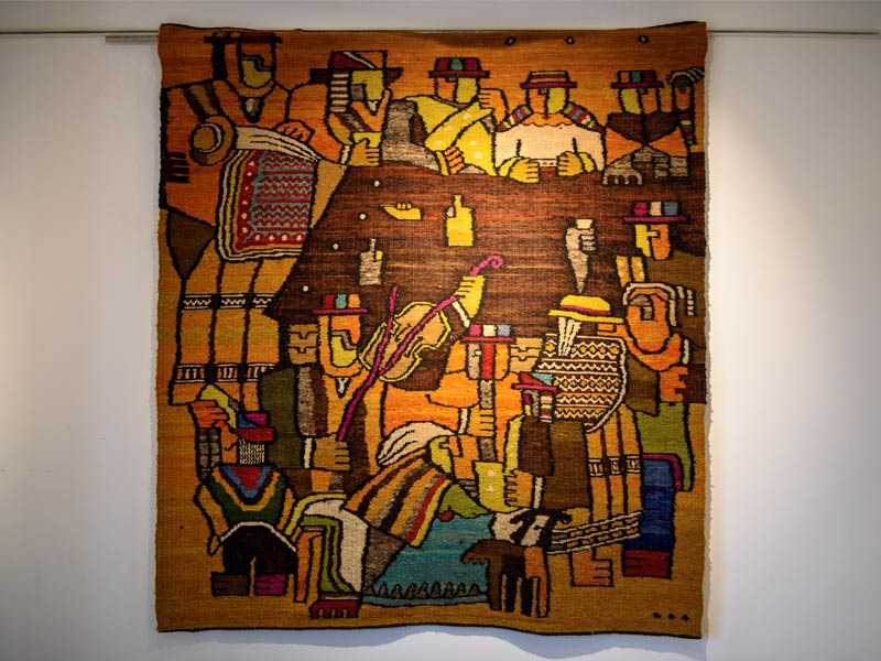 A vibrantly coloured rug hangs on a white wall - Beautiful Homes