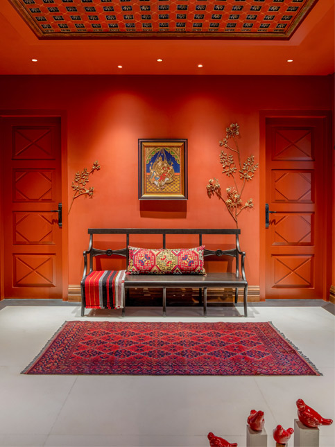 This vibrant corridor by Shabnam Gupta, featuring bold red walls and a patterned ceiling – Beautiful Homes