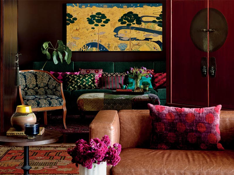 Pavitra's den, with Havana Cigar-toned walls, features a custom leather sofa, yellow artwork, and richly layered textiles – Beautiful Homes