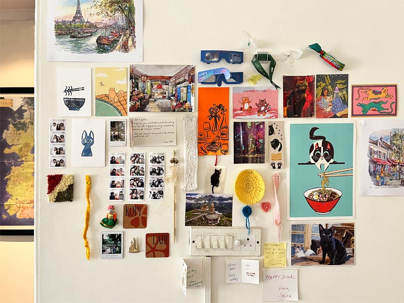 Eclectic photo wall with travel-themed art, polaroids, cat illustrations, crochet accents, and colourful mementos – Beautiful Homes
