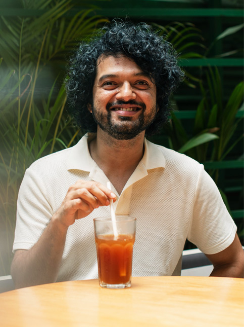 Man enjoying an iced drink in a lush green café setting – Beautiful Homes