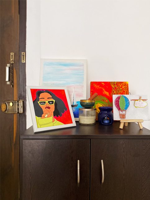 Modern art display on a dark wooden cabinet with colourful paintings, candles, string art, and décor – Beautiful Homes
