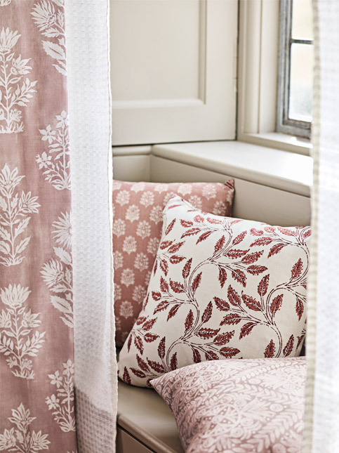 Cozy corner featuring decorative pillows with floral patterns, partially hidden by soft curtains - Beautiful Homes