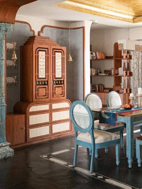 Dining room with a carved wooden hutch, blue chairs, and ornate blue columns, blending traditional and modern décor - Beautiful Homes