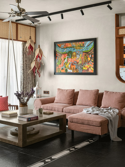 A cozy living room with a large pink coloured sofa, a wooden coffee table, and a black track light fixture on the ceiling - Beautiful Homes