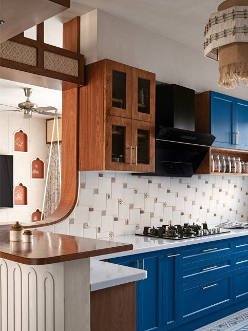 A modern kitchen with deep blue lower cabinets, a gas cooktop, wooden upper cabinets - Beautiful Homes