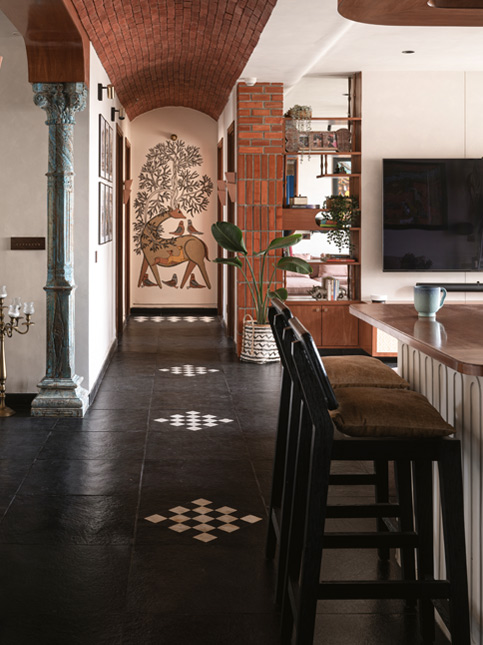 A long hallway with a low ceiling made of exposed red bricks, black tiled floors, and decorative art on the walls - Beautiful Homes