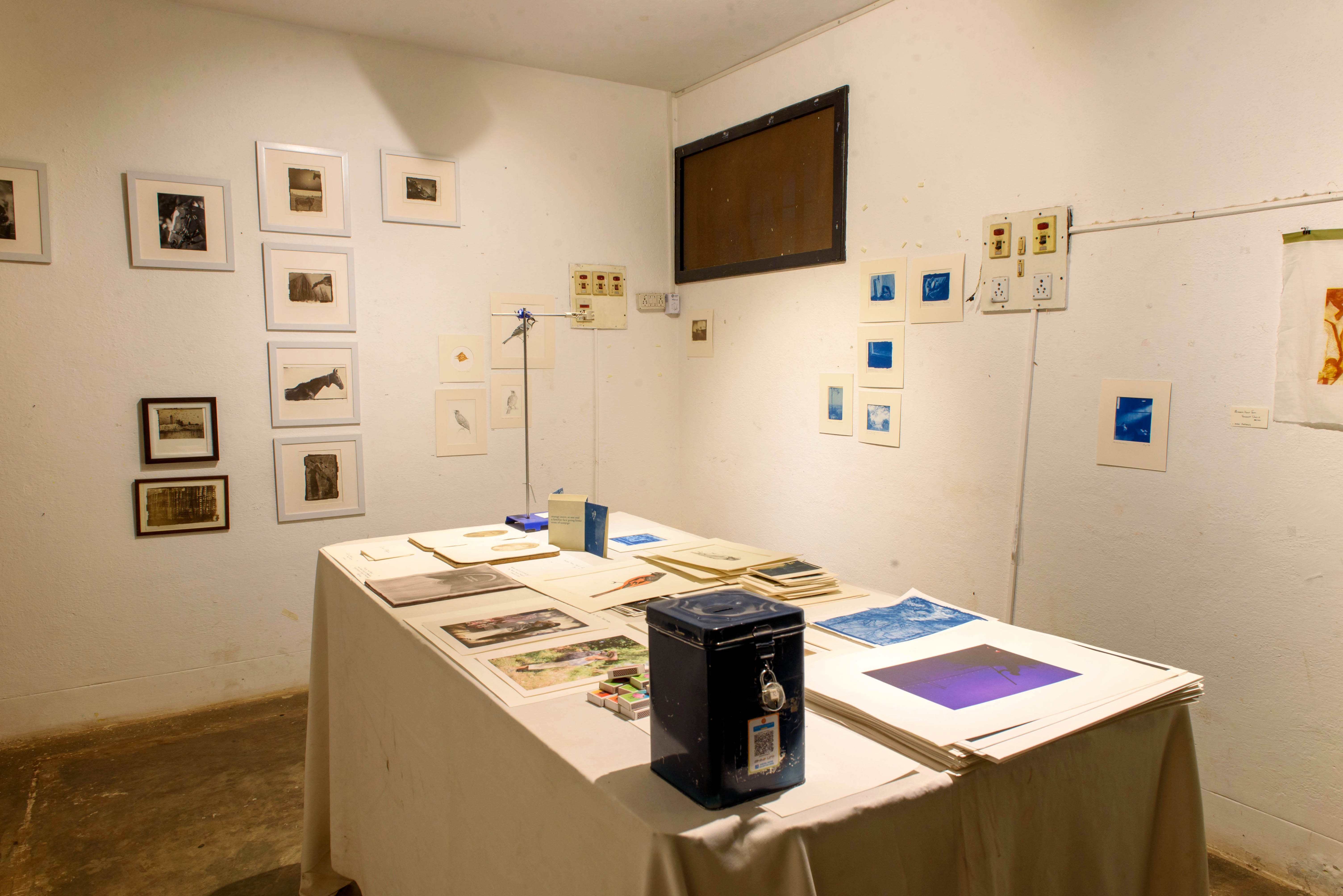 An art exhibition room featuring framed artworks on the walls and a central table displaying prints and art supplies – Beautiful Homes