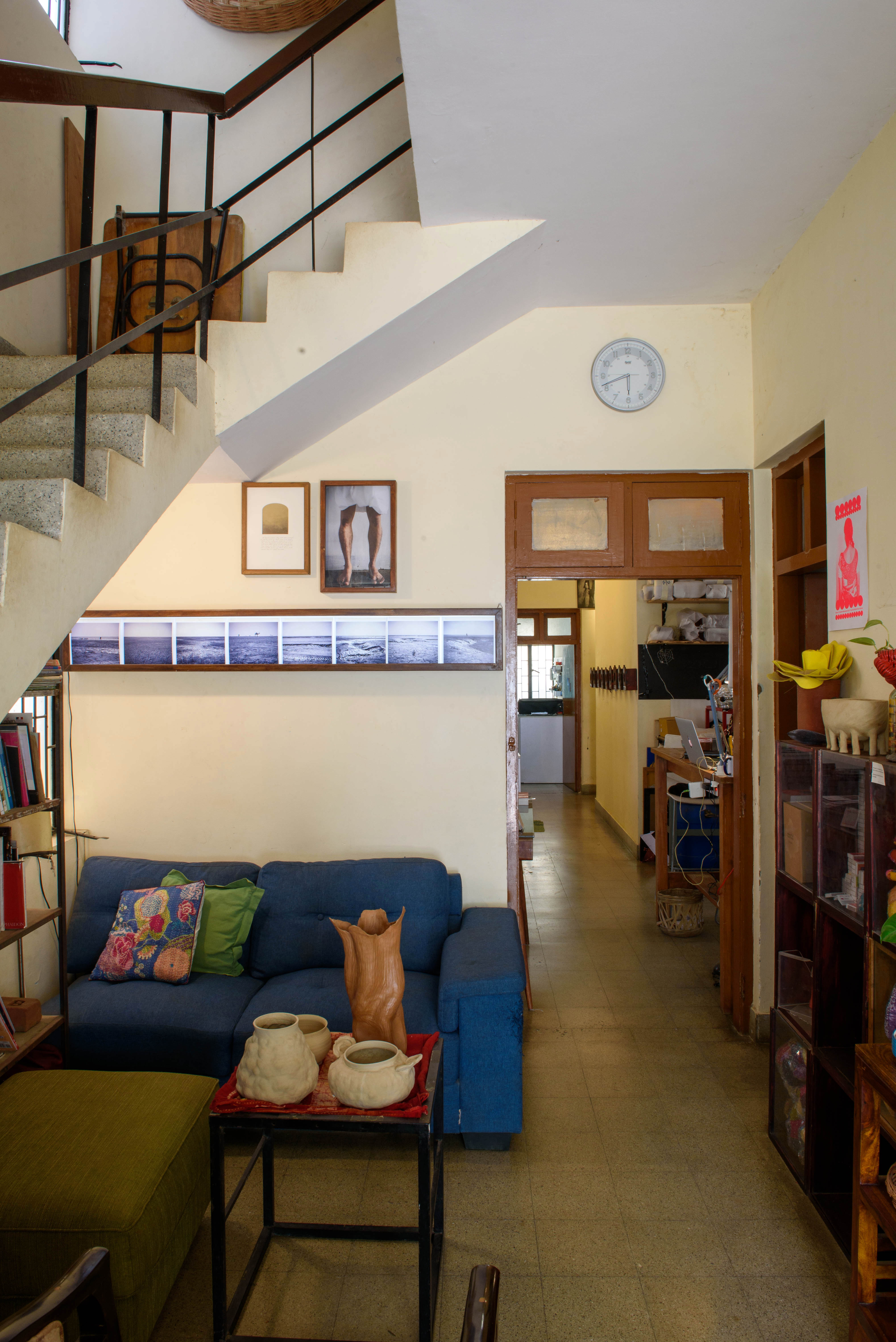 A cozy living room with a blue sofa, artwork on the wall, and a staircase leading upstairs – Beautiful Homes