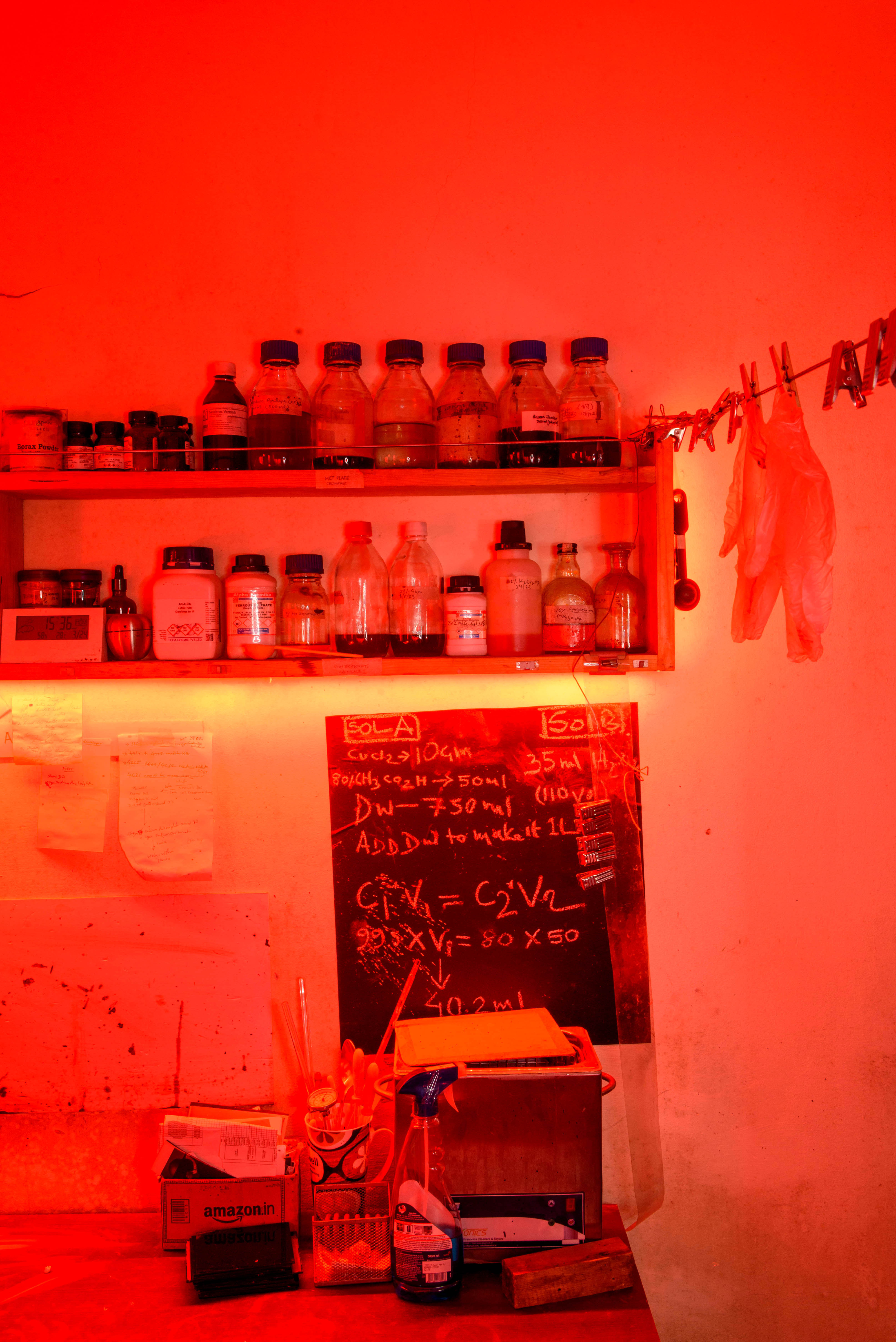 A shelf filled with bottles and a blackboard with chemical formulas, all bathed in a vivid red light, likely in a darkroom – Beautiful Homes
