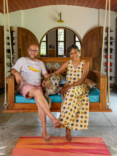 A candid shot of a happy couple and their dog relaxing on a traditional wooden swing inside their home - Beautiful Homes