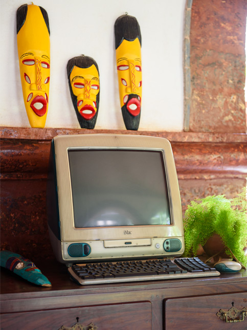 A vintage, beige coloured Apple iMac G3 computer with a matching keyboard sitting on a dark wooden cabinet - Beautiful Homes