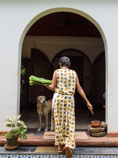 A woman and a dog at the entrance of a house, which has a white arched doorway and a small step - Beautiful Homes