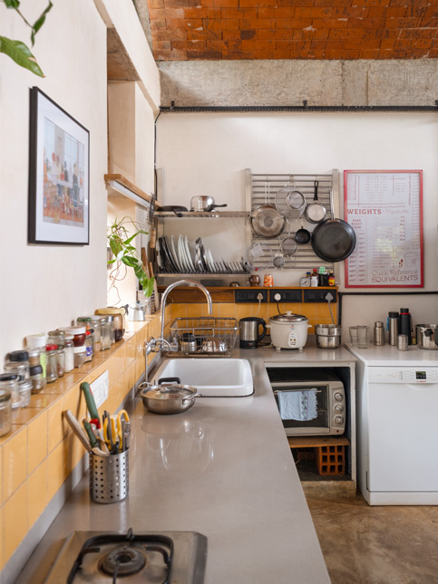 A compact kitchen features a vaulted brick ceiling, mustard yellow subway tile backsplash, and open shelving above concrete countertops – Beautiful Homes