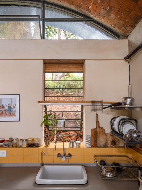 The kitchen has a custom-built hob, deep counters, open shelving and a wide utility sink. Finished with yellow tile and vaulted brick ceilings, the space balances efficiency with warmth – Beautiful Homes