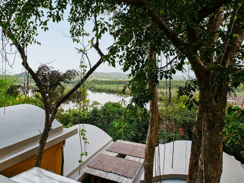 From the road above, the home’s curved vaulted roofs peek through the trees, set against a backdrop of tidal backwaters in Olaulim, a quiet village in North Goa where the family lives and works – Beautiful Homes