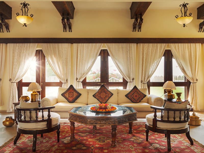 Sunlit lounge at Mihir Garh with carved furniture and rich textiles – Beautiful Homes