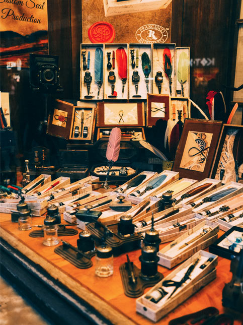 A crowded display in a shop window features numerous quill pens, dip pens, and wax seal kits – Beautiful Homes