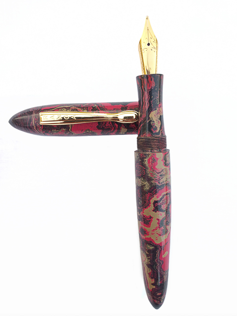 A close-up of a red, black, and gold marbled ebonite fountain pen with a gold nib – Beautiful Homes