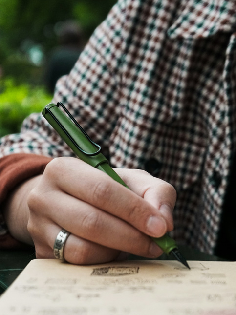 A person writing in a notepad with a green fountain pen – Beautiful Homes