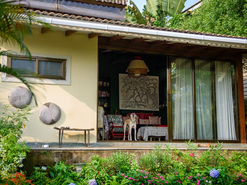 Charming Goa home with lush garden view and pet dog standing at the entrance – Beautiful Homes