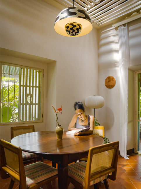 Woman reading at a sunlit round dining table – Beautiful Homes