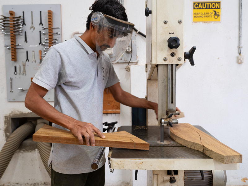 Carpenter Leeladhar shapes teak slats on the bandsaw, wearing the safety gear required throughout the workshop – Beautiful Homes