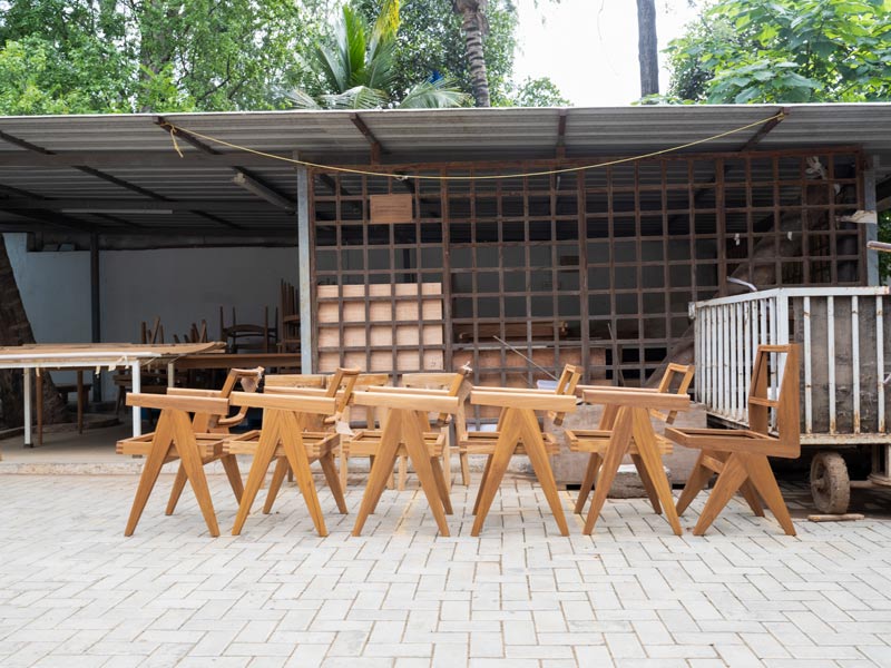Chandigarh chairs in natural teak finish rest near the polishing unit, aerating after their first coat – Beautiful Homes