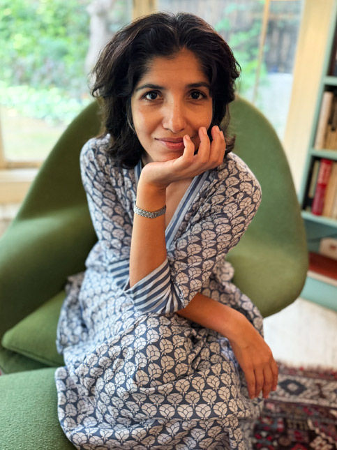 Chiki Sarkar sitting on a green armchair in a cozy home library – Beautiful Homes