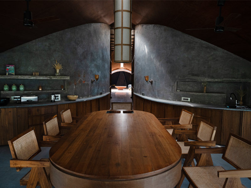 Curved concrete dining space with wooden table – Beautiful Homes